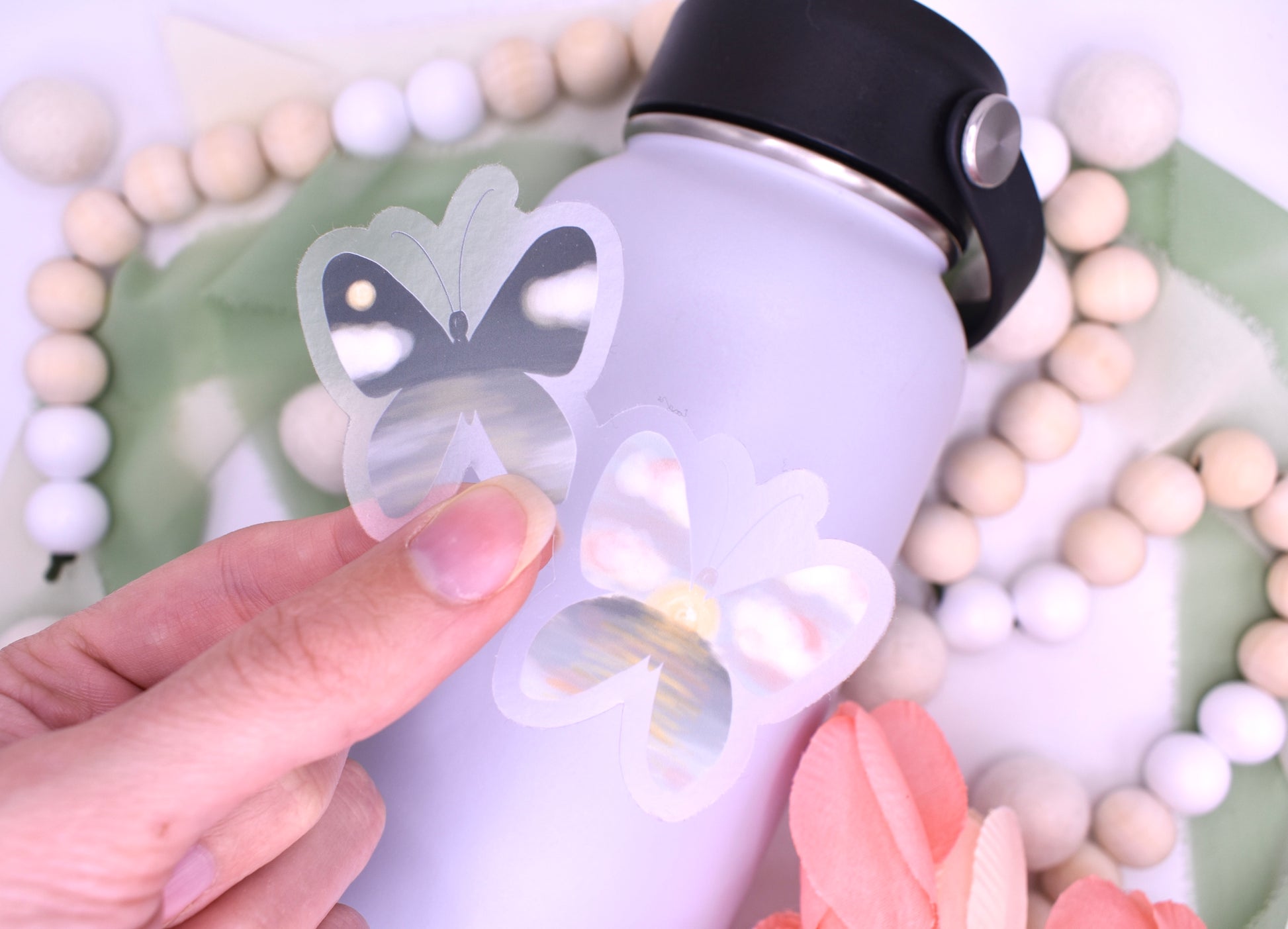 Night and day beach/ocean inspired butterflies- clear background sticker held over a grey waterbottle